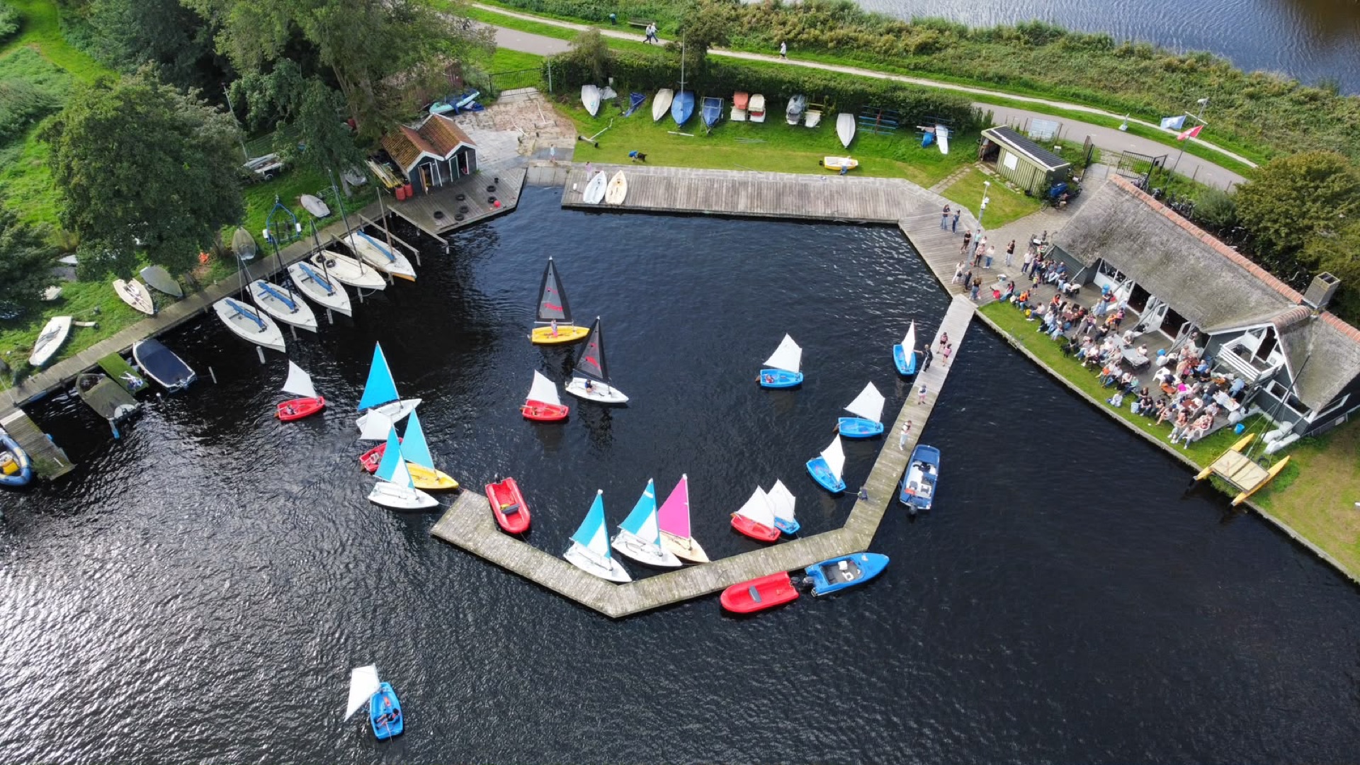 Vanuit de lucht: de haven van WSV De Breek aan het Twiske, met kleurige Opti's en Valken langs de steigers.