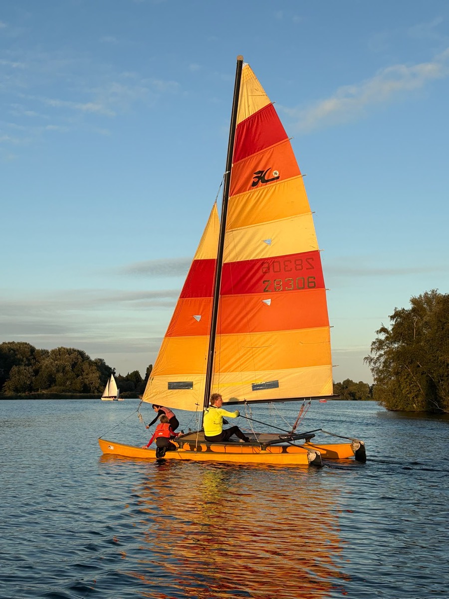 Hobie-catamaran met oranje-rood zeil bij avondzon op het Twiske.