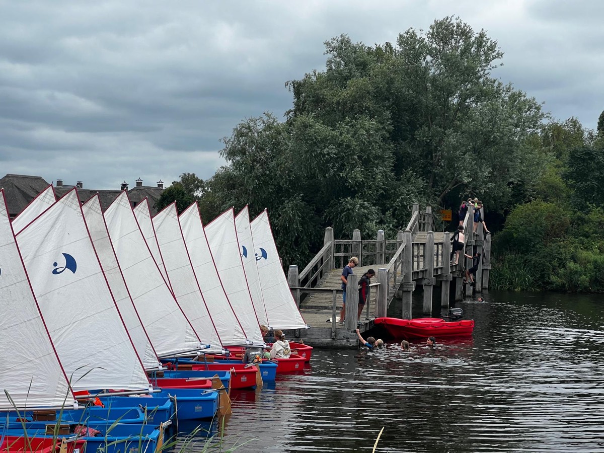 Rij Optimisten langs de houten steiger op een bewolkte zomerdag.